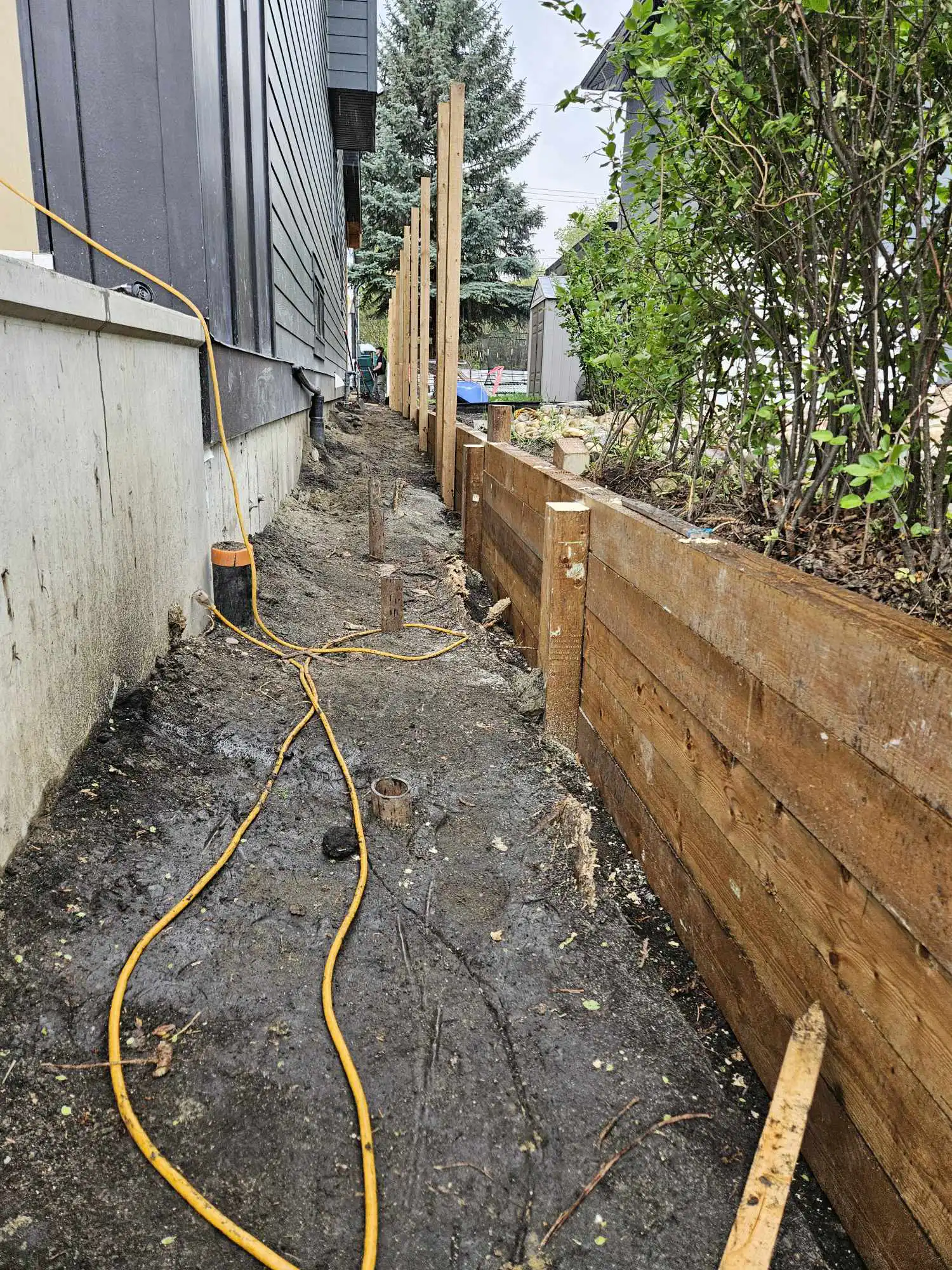 4x6 pressure-treated posts concreted in place for a structural retaining wall on an Edmonton infill lot