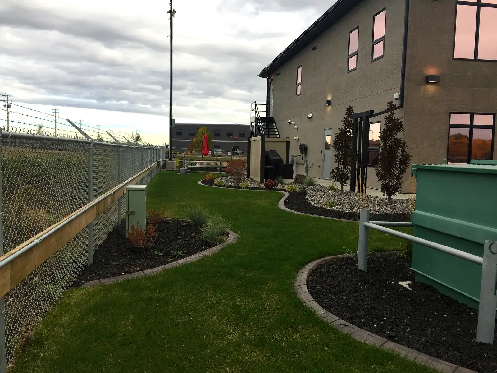Commercial grounds landscaping with curved beds, sod, and shrubs in Edmonton
