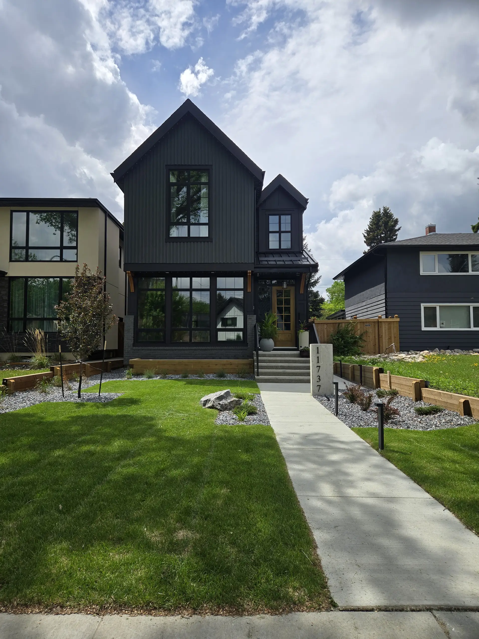 Completed infill lot landscaping in Edmonton with structural wood retaining wall and rebuilt fence